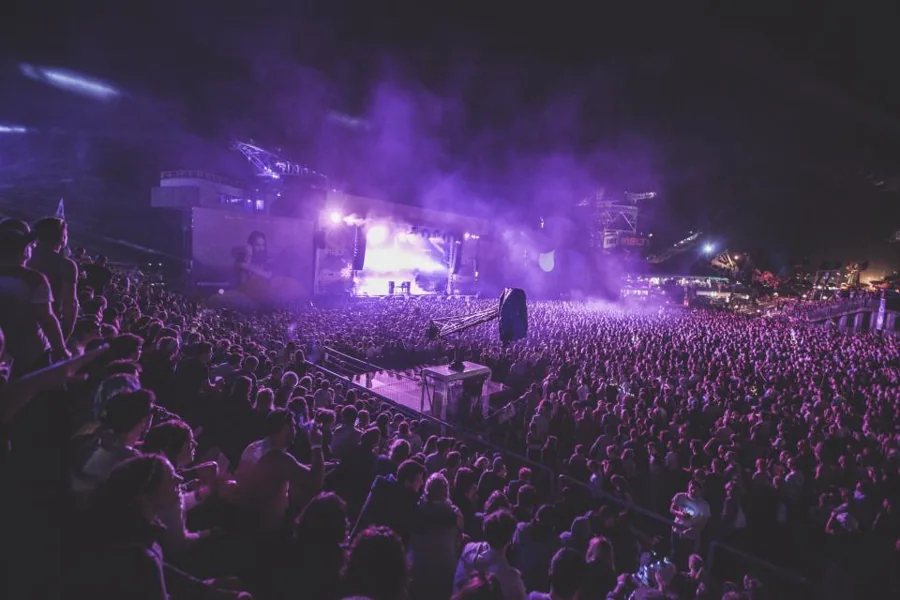 Packed arena during a live show with purple lighting